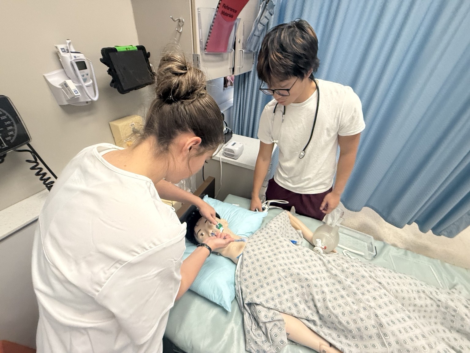 Students practicing clinical skills with a training mannequin