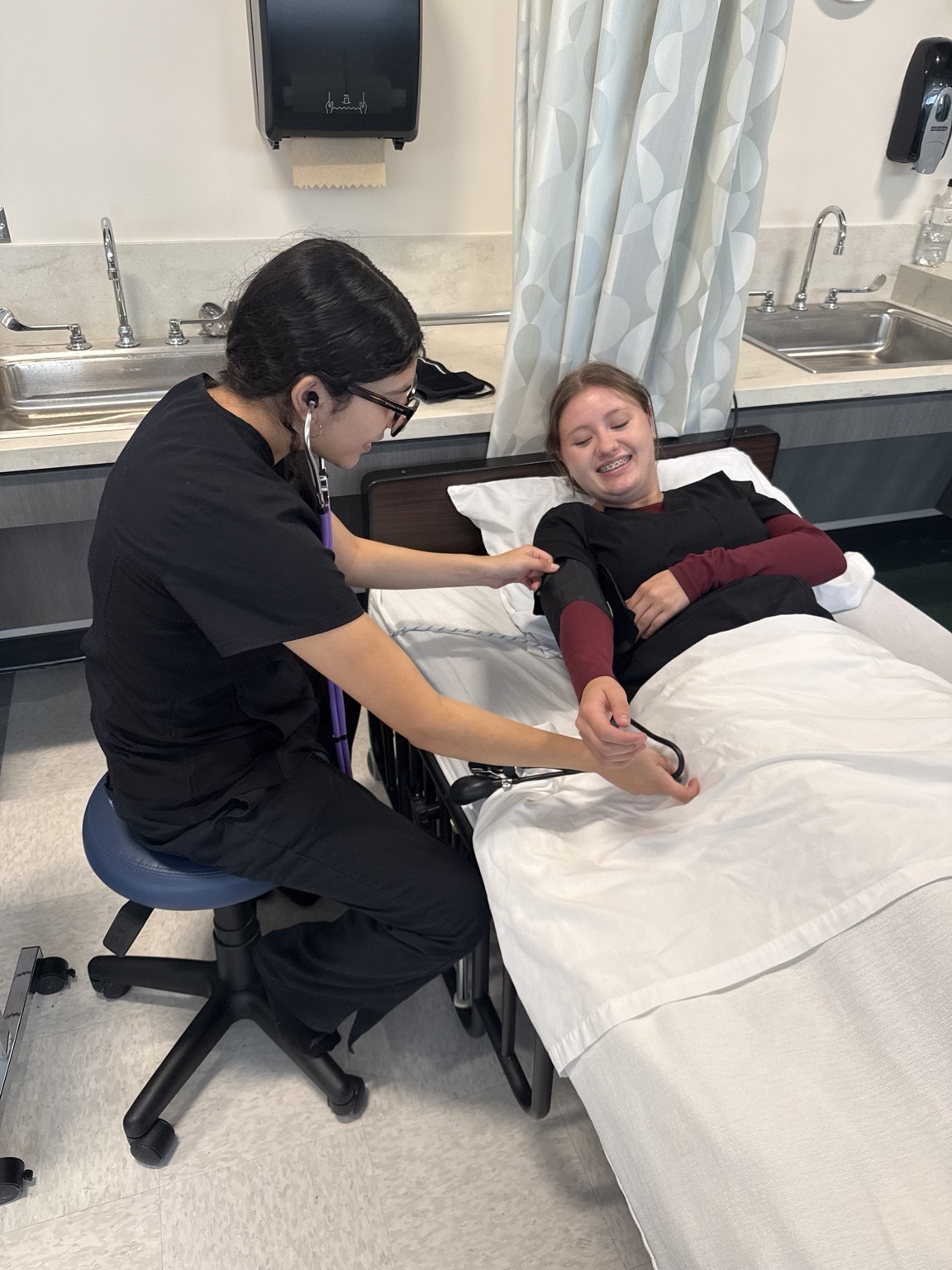 A student practicing a blood pressure measurement with a peer